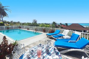Zona de piscina con piscina, sillas de descanso y una mesa con bebidas y vasos.