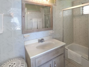 Un baño con lavamanos, espejo y bañera.