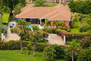 A house with a swimming pool, surrounded by lush greenery and palm trees.