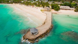 An aerial view of a beach resort with a long pier leading to a small hut, surrounded by turquoise waters and a sandy beach. - Summertime, Silver Sands,4BR (Duncans)