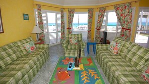 A room with a yellow wall, green plaid furniture, and a colorful rug. - Sol Mar, Silver Sands 3BR (Duncans)