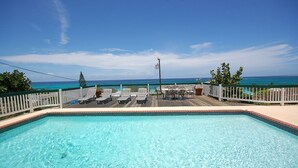 A pool with clear blue water, surrounded by a wooden deck and white railings. - Sol Mar, Silver Sands 3BR (Duncans)