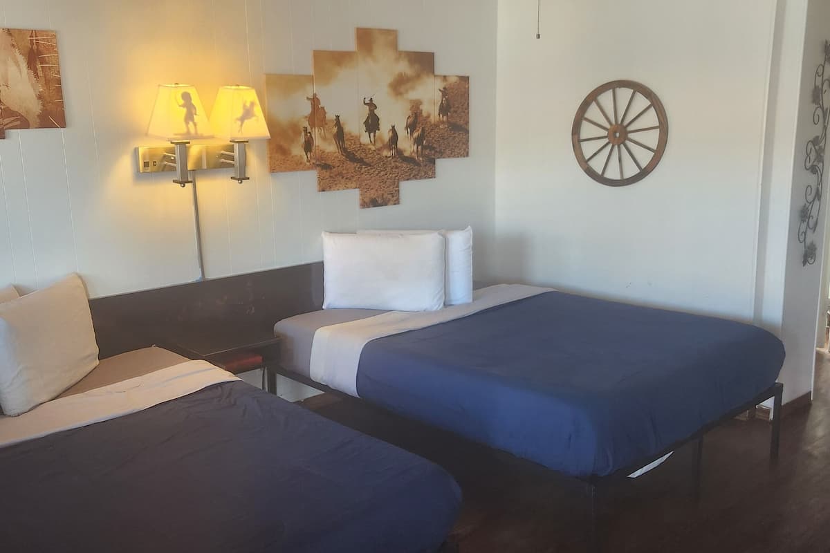 Habitación de hotel con dos camas, una lámpara de pared y una rueda decorativa.