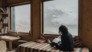 A cozy room with a large window, a wooden desk, and a bed with a striped blanket. - Puesto Cagliero refugio de montaña (El Chalten)
