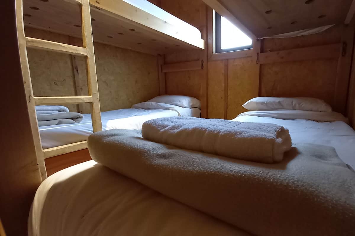 Eine Holzhütte mit Stockbetten, einer Leiter und einem Fenster.