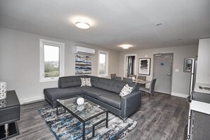 A modern living room with a sectional sofa, a coffee table, and a dining area with a table and chairs.