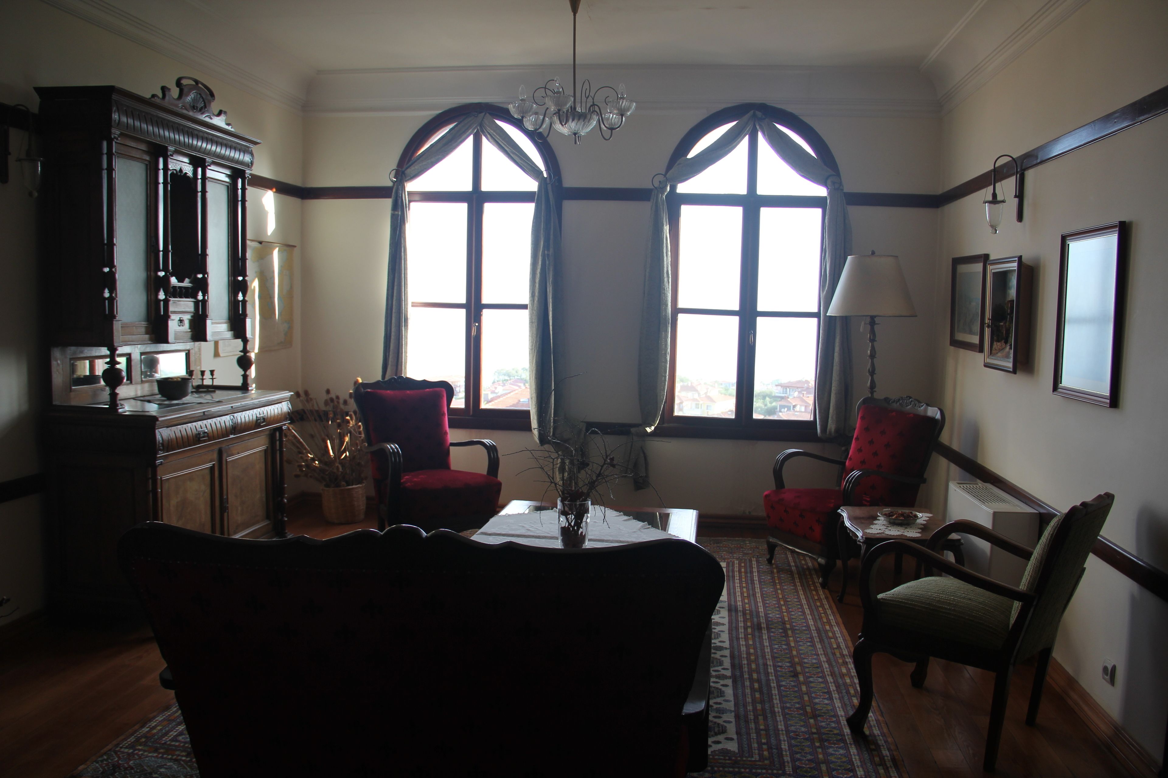 A dining area with a table, chairs, a chandelier, and large windows.