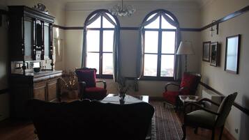 A dining area with a table, chairs, a chandelier, and large windows.