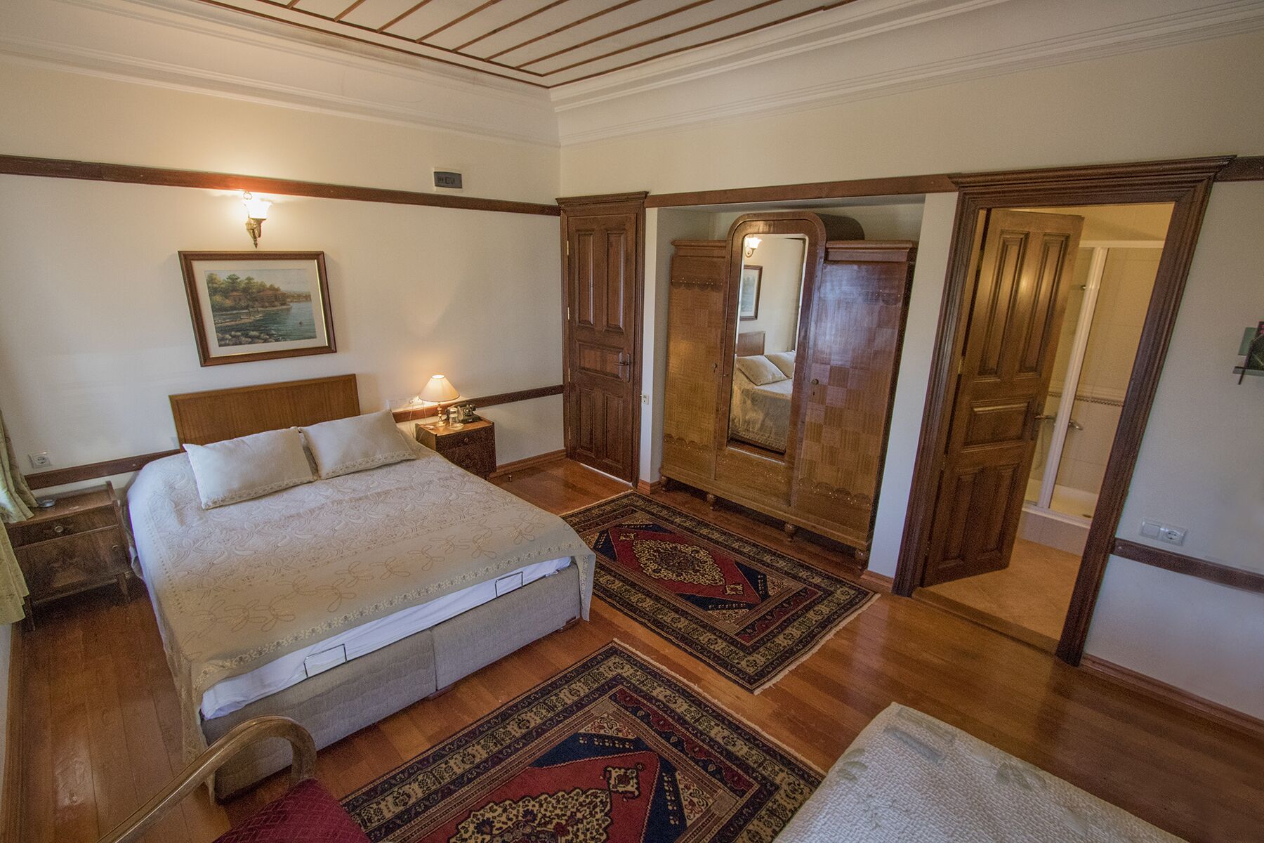 Un dormitorio con una cama grande, una mesita de noche, un espejo y un armario.