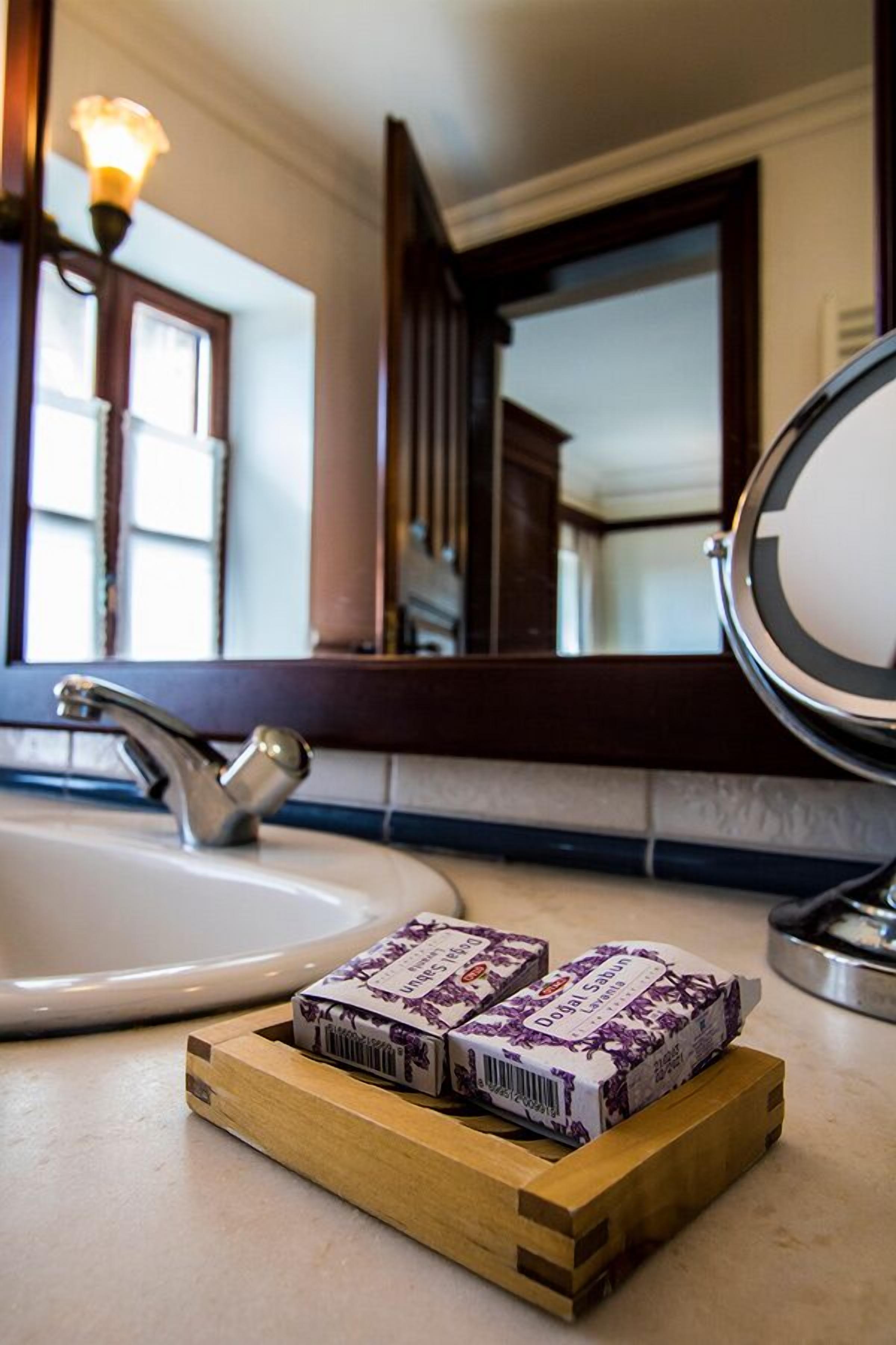 A bathroom with a sink, mirror, and wooden tray holding two bars of soap.