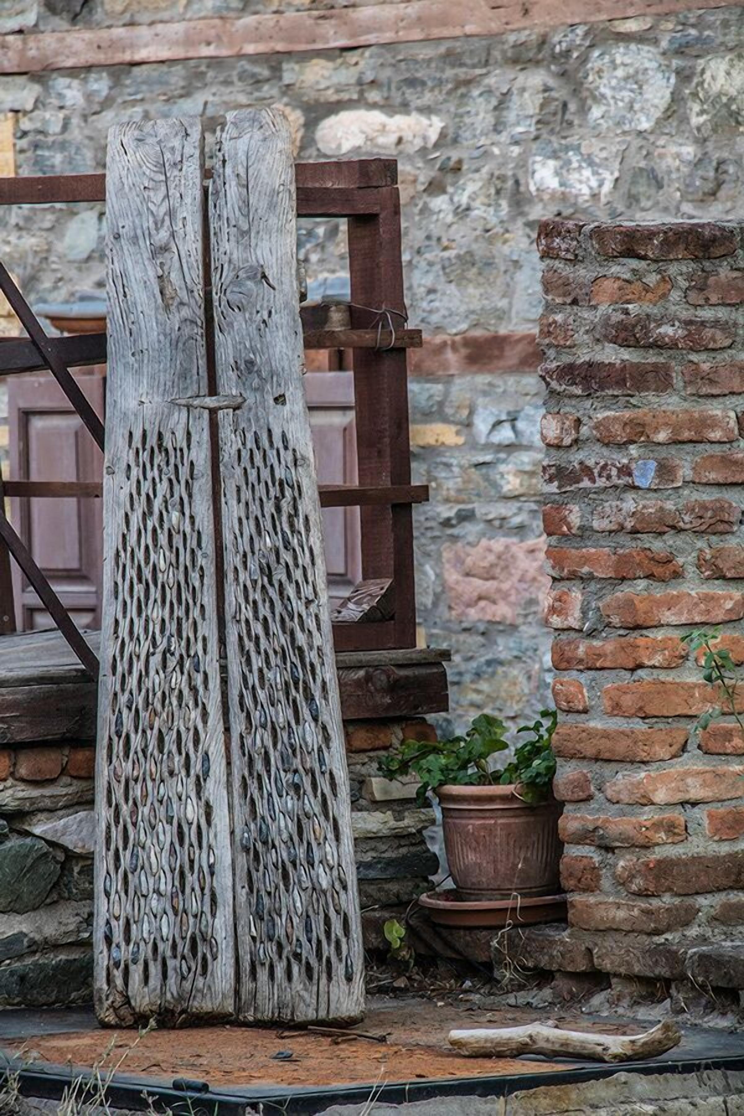 A rustic wooden structure with a textured surface, a brick wall, and a potted plant.