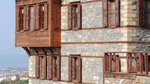 A stone building with a tiled roof and wooden window shutters.