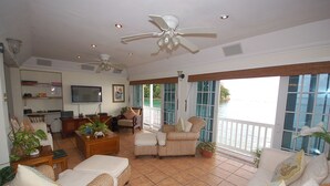 A spacious living area with a television, comfortable seating, and a view of the outdoors. - San Cove, Blue Lagoon, Port Antonio 4BR (Port Antonio)