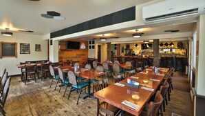 En restaurant med træborde og stole, et barområde og en aircondition på loftet.