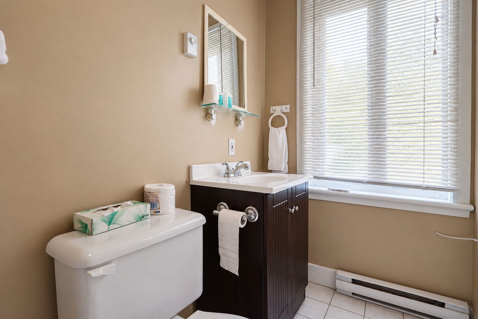Un baño con inodoro, lavamanos y ventana con persianas.