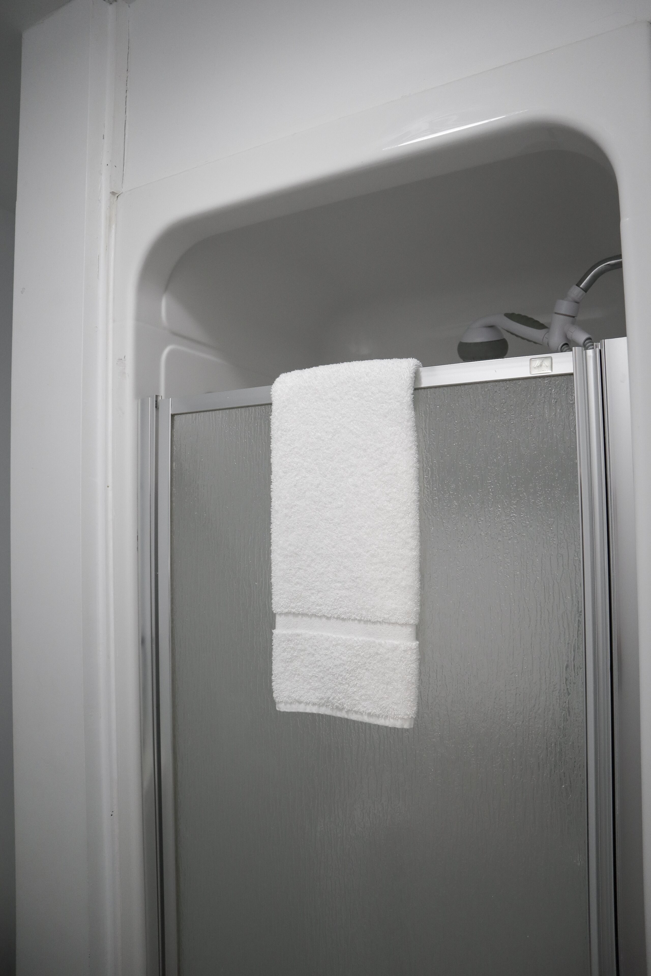 Een badkamer met een witte handdoek aan een glazen douchedeur.