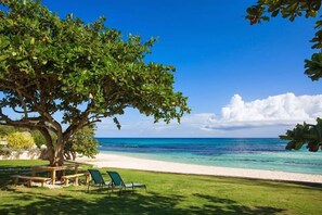 A beach scene with a large tree, a grassy area, and a clear blue sky. - Villa Mara, Ocho Rios Jamaica Villa 6BR (Ocho Rios)