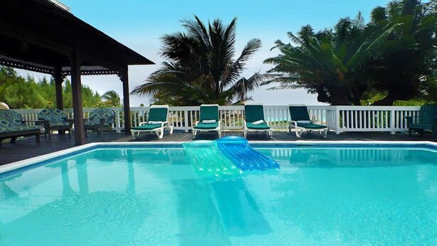 A swimming pool with green lounge chairs and a white fence. - Sea Spray 50 Steps to the Sea, Silver Sands, 3 BR (Duncans)