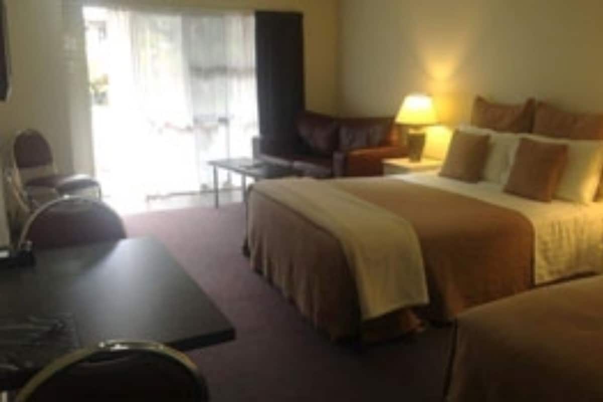 Una habitación de hotel con una cama, un escritorio, una silla y una lámpara.