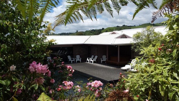 Un espace extérieur abrité avec des chaises blanches et une piscine.