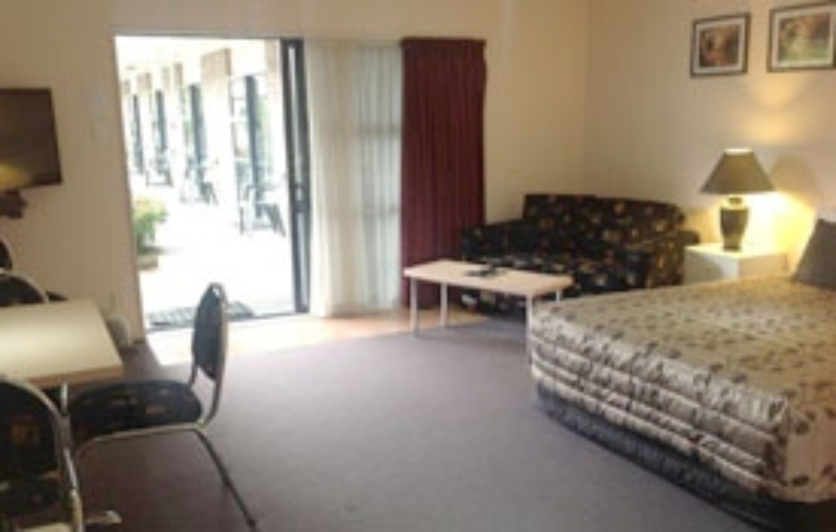 Une chambre d’hôtel avec un lit, un bureau, une chaise, un canapé et une fenêtre avec des rideaux.