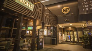 Una entrada de hotel moderna con un cartel que muestra las marcas 'Roccia' y 'HP', indicando una residencia con comercios.