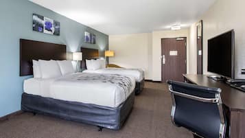 A hotel room with two beds, a desk with a TV, and a chair.