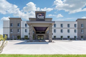 Edificio de Sleep Inn & Suites con diseño moderno, que presenta techo plano, fachada de piedra y una entrada amplia.