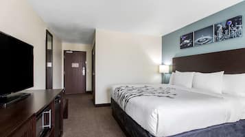 A hotel room with a large bed, a flat-screen TV, a wooden dresser, and a wall-mounted artwork.