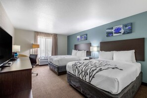 A hotel room with two beds, a desk with a computer, a TV, and artwork on the wall. - Sleep Inn & Suites Ankeny - Des Moines (Ankeny)