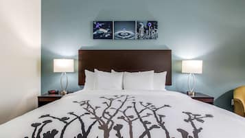 Una habitación de hotel con una cama grande, dos mesitas de noche con lámparas, una obra de arte en la pared y una silla.