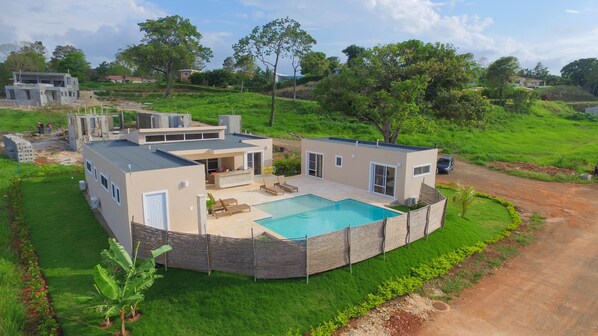 A modern house with a swimming pool, a patio, and a well-maintained lawn.