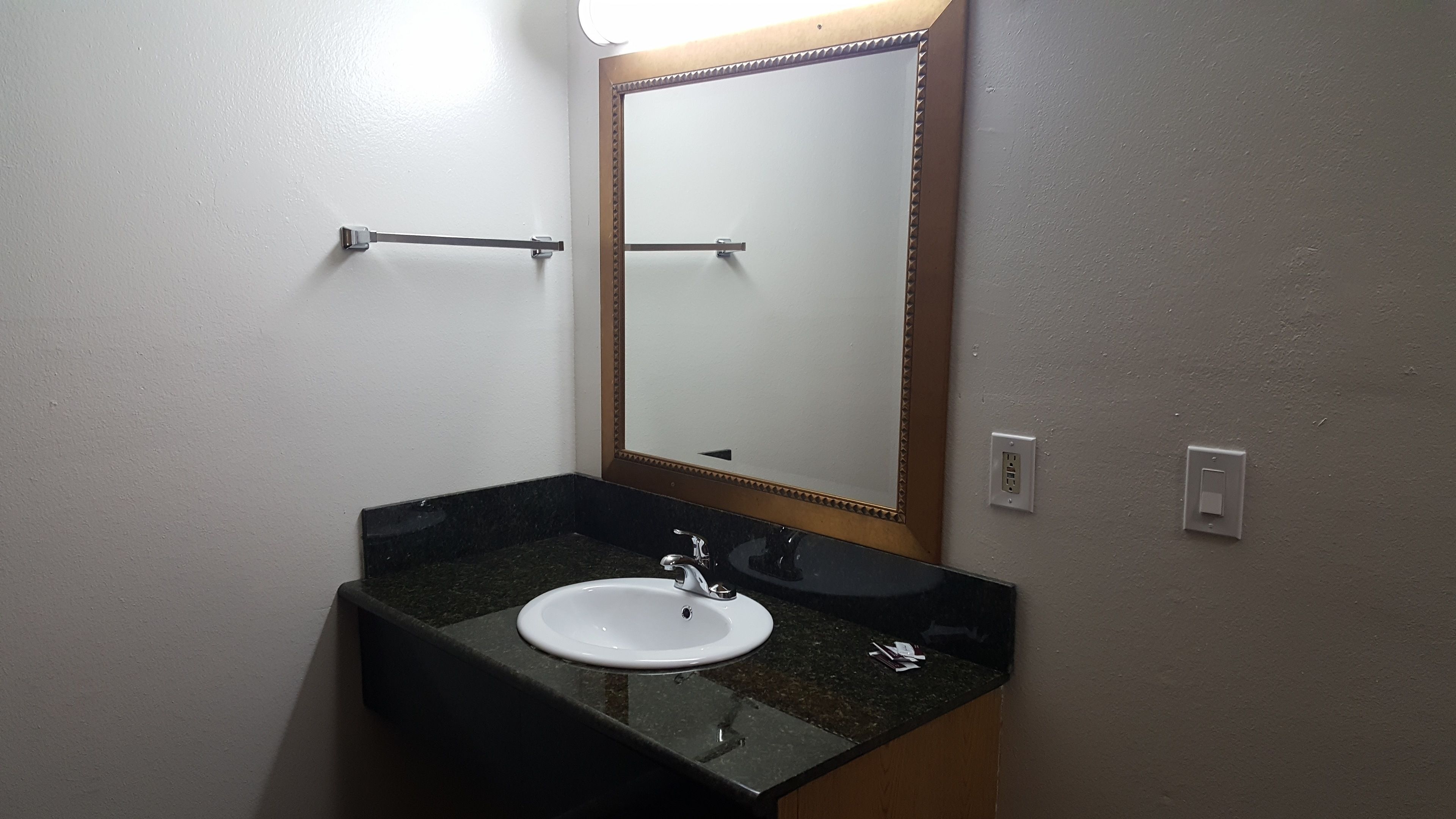A bathroom with a white sink, a mirror with a wooden frame, and a towel rack.