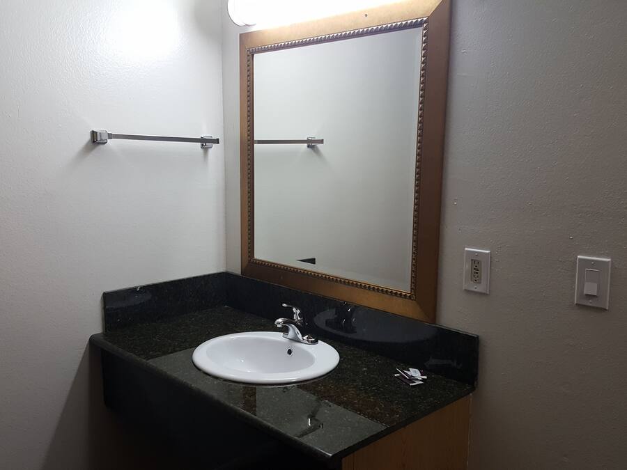 A bathroom with a white sink, a mirror with a wooden frame, and a towel rack.