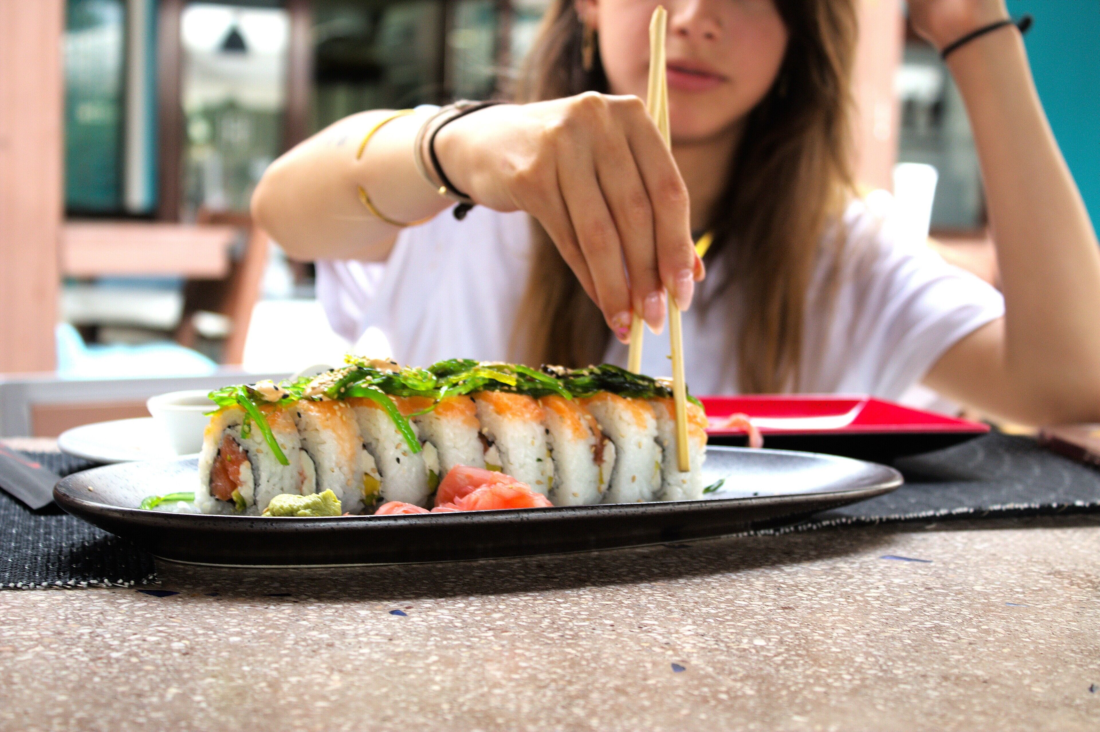 A sushi dish on a plate with chopsticks.