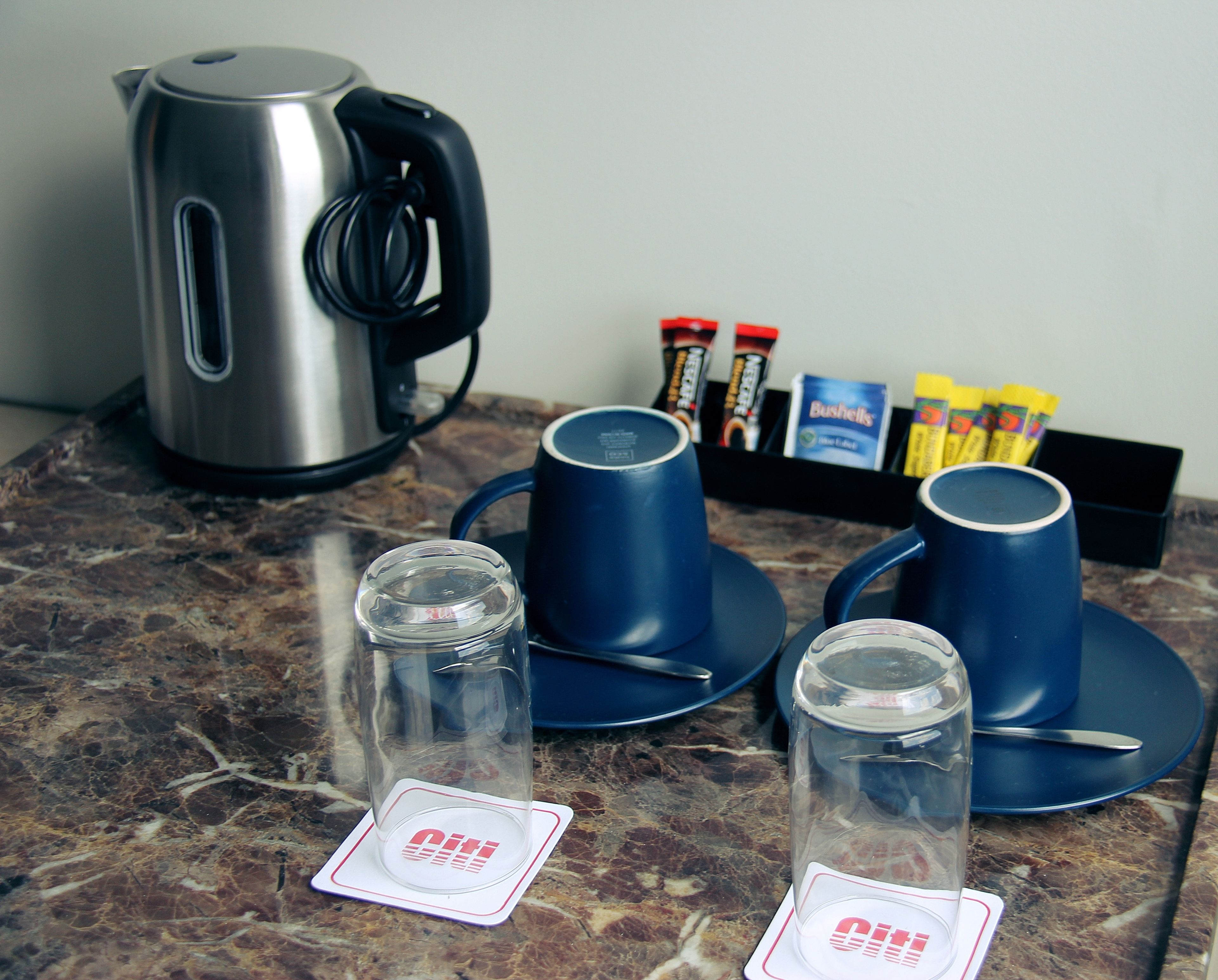 A kitchen counter with a kettle, two blue cups, and two glass jars with lids.
