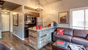 Una cocina moderna con una isla central, un comedor con un sofá de cuero marrón y un ventanal grande.