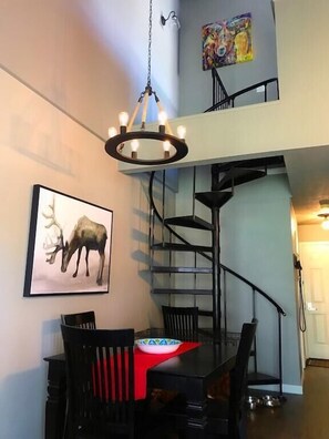 Un comedor con una araña, una escalera y un cuadro de un ciervo en la pared.