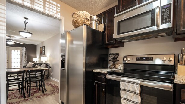 A modern kitchen with stainless steel appliances, a dining area with a table and chairs, and a ceiling fan. - Less than 2 miles to Downtown and sleeps 6.  (Athens)