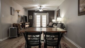 A dining area with a wooden table and chairs, a ceiling fan, and a view of the living room through a glass door. - Less than 2 miles to Downtown and sleeps 6.  (Athens)