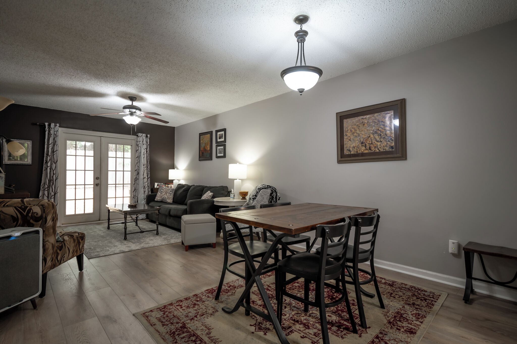 Un salon comprenant une table à manger, des chaises, un canapé et un ventilateur de plafond.