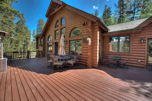 A log cabin with a deck, outdoor seating, and large windows.