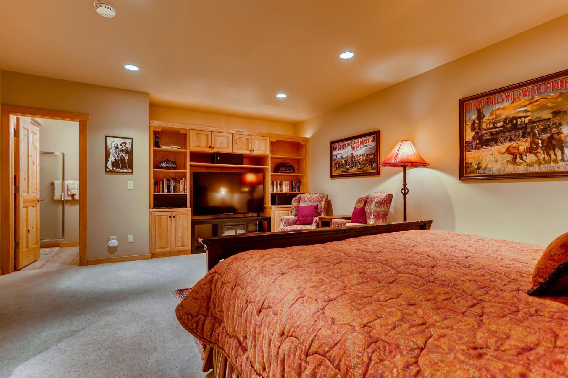 A bedroom with a large bed, a wooden wardrobe, a TV, and a poster on the wall.