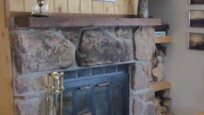 Una chimenea de piedra con puerta de cristal, una reja dorada y un estante con un cartel que dice '¡Lo siento!'. 