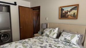 Un dormitorio con cama, un cuadro, lavadora y armario.