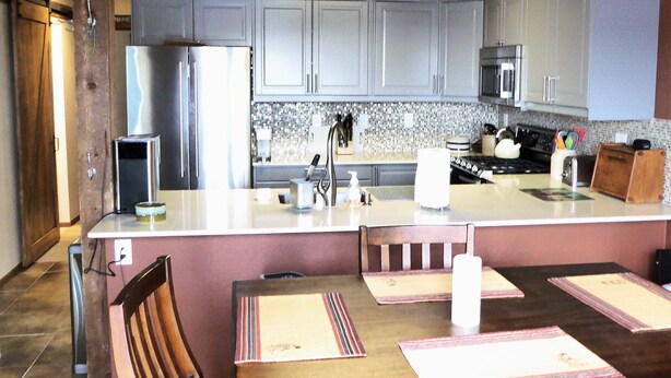 Una cocina con isla central, sillas de madera, una mesa de comedor y un refrigerador.