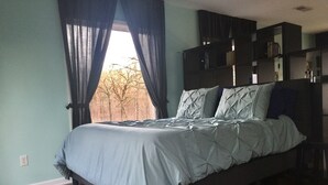 Un dormitorio con cama, ventana con cortinas y estanterías empotradas.
