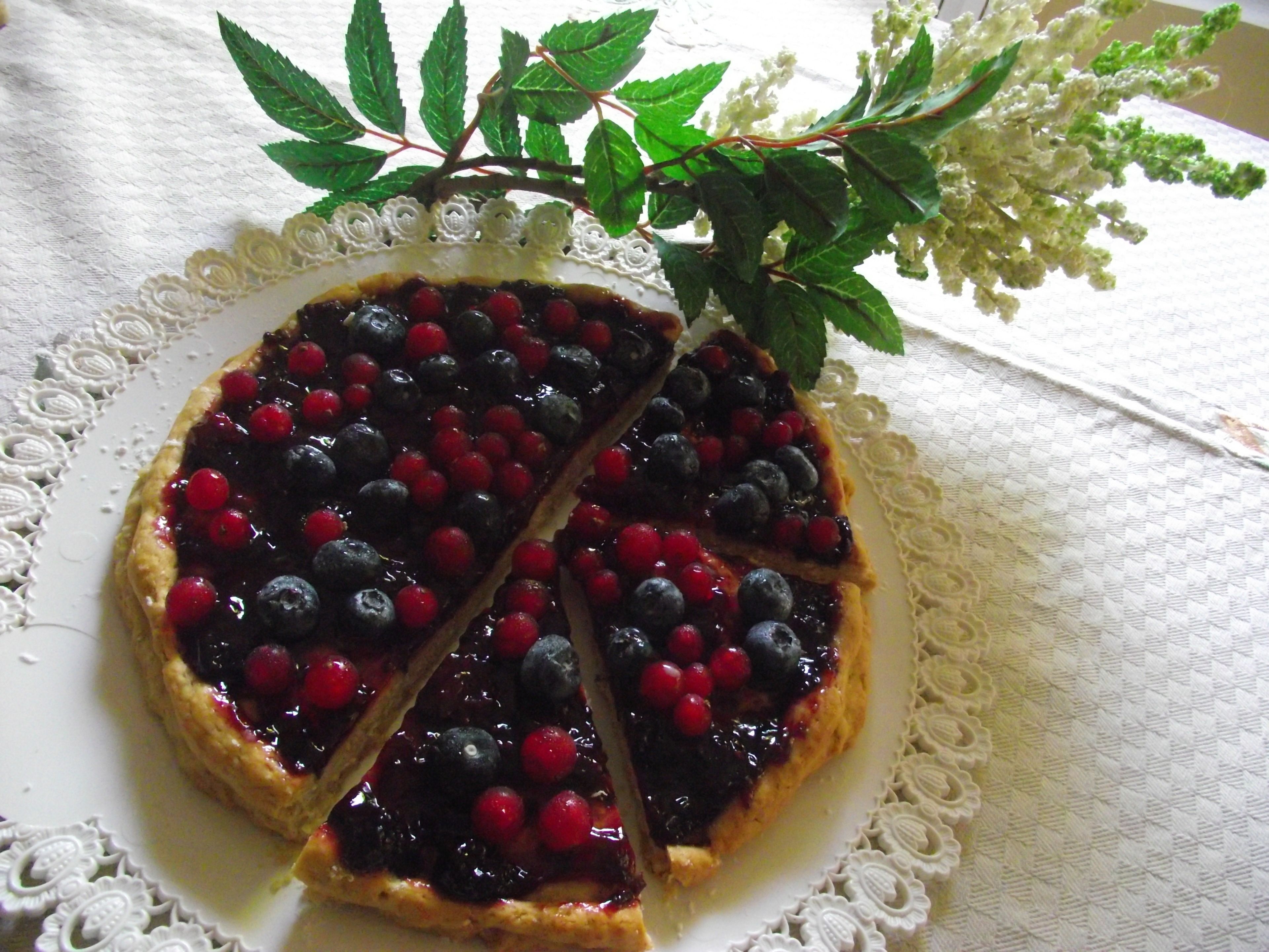 Tarta de frutos rojos sobre un plato blanco con encaje.