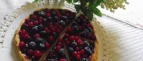 Tarta de frutos rojos sobre un plato blanco con encaje.