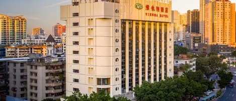 Un hotel de varios pisos con un letrero llamativo, rodeado de otros edificios y una calle concurrida.